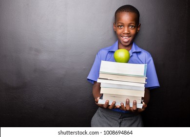 Young Atractive Black Boy Wearing School Unifor While Holding His School Books And A Green Apple, Looking Excited About Going Back To School.