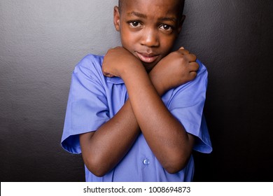 Young Atractive Black Boy Wearing School Unifor Looking Sad While Hugging Himselfin A  Worried Manner, Going Back To School.