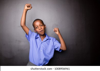 Young Atractive Black Boy Wearing School Unifor Looing Strong And Configent Going To School For The First Time With His Arms In A Air Fist Pump Motion.