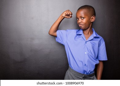 Young atractive black boy wearing school unifor looing sad and worried going to school for the first time with his one arm making flexing his muscle.