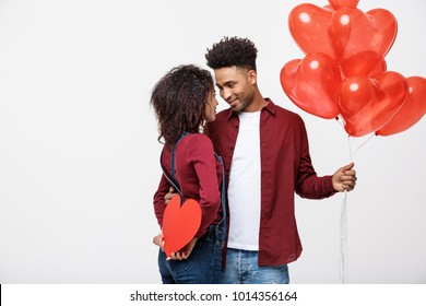 Young attactive African American couple holding heart balloon and paper.