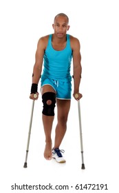 Young Attractive African American Man Athlete On Crutches, Wearing A Wrist Brace And Knee Support,  Bandaged. White Background. Studio Shot.