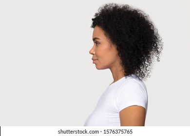 Young attractive African American woman standing in profile, beautiful millennial female with curly hair, confident serious model looking at copy space, leadership, isolated on studio background