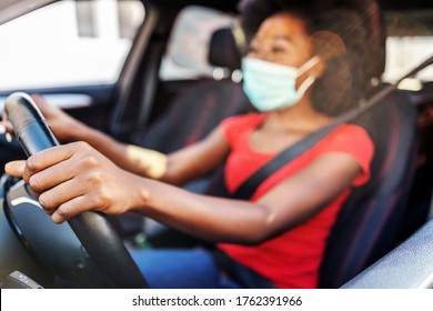 Young attractive african woman with mask on her face driving her car during covid-19 pandemic.
