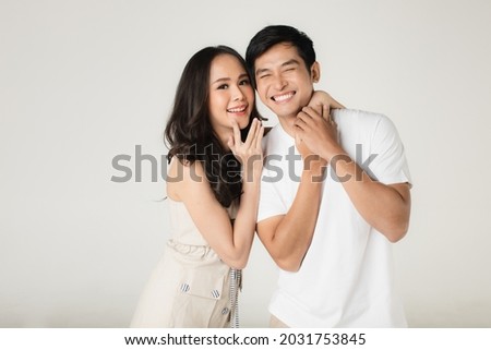 Young attractive Asian couple, man wearing white t shirt and beige pants, woman wearing beige dress. Teasing each other. Concept for pre wedding photography.