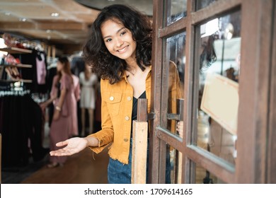 Young Attractive Asian Fashion Shop Owner At Her Store Opening The Door For Customer