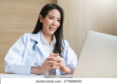 Young Attractive Asian Female Doctor Diagnosis Talking And Looking To Camera In Video Conference ,Positive Doctor Waving And Having Online Consultation On Digital Tablet Laptop