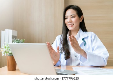 Young Attractive Asian Female Doctor Diagnosis Talking And Looking To Camera In Video Conference ,Positive Doctor Waving And Having Online Consultation On Digital Tablet Laptop