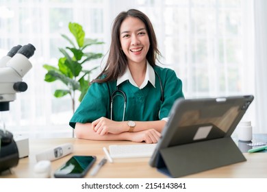 Young Attractive Asian Female Doctor Diagnosis Talking And Looking To Camera In Video Conference ,Positive Doctor Waving And Having Online Consultation On Digital Tablet Laptop