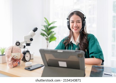 Young Attractive Asian Female Doctor Diagnosis Talking And Looking To Camera In Video Conference ,Positive Doctor Waving And Having Online Consultation On Digital Tablet Laptop