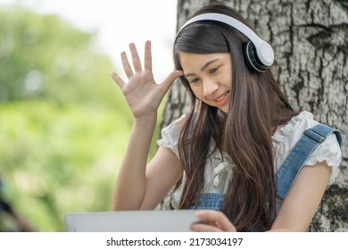 Young Attractive Asian Female Employee Wear Earphone Listen To Digital Online Course Development Study Online In The Park