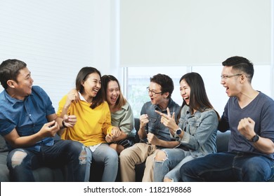Young Attractive Asian Group Of Friends Talking And Laughing With Happy In Gathering Meeting Sitting At Home Feeling Cheerful And Enjoy Game In Leisure Time Together. People In Blue Or Yellow Wearing.