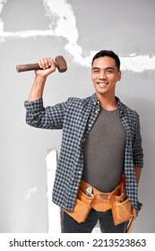 A Young Attractive Asian Man Holds Up A Mallet With Strong Arm Doing Home DIY