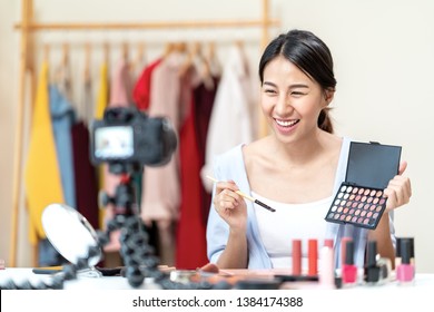 Young attractive asian woman beauty blogger or vlogger smiling looking at camera and talking on video shooting while make up. Social media young asian micro influencer in relax casual style at home.