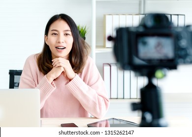 Young attractive asian woman blogger or vlogger looking at camera and talking on video shooting with technology. Social media influencer people or content maker concept in relax casual style at home. - Powered by Shutterstock