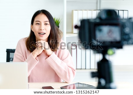 Young attractive asian woman blogger or vlogger looking at camera and talking on video shooting with technology. Social media influencer people or content maker concept in relax casual style at home.