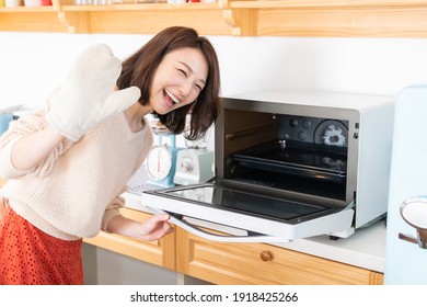 Young Attractive Asian Woman Cooks In A Kitchen,oven,