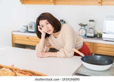 young attractive asian woman cooks in a kitchen,worry