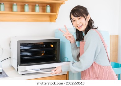 Young Attractive Asian Woman Cooks In A Kitchen,oven,