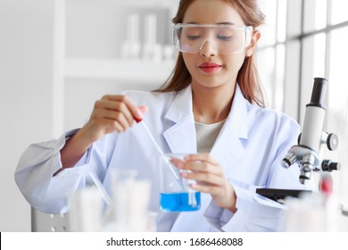 Young Attractive Asian Woman Medical Laboratory Technologist  Wearing White Lab Coat Working In Laboratory Room.