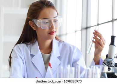 Young Attractive Asian Woman Medical Laboratory Technologist  Wearing White Lab Coat Working In Laboratory Room.