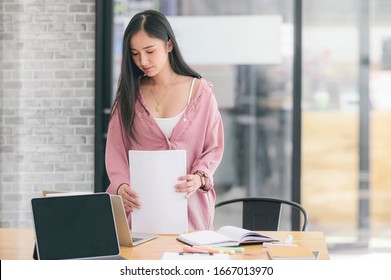 Young Attractive Asian Woman Prepare To Keep Documents To Finish Work While Standing At Office Desk.