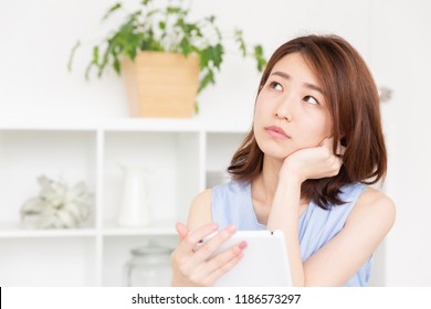 young attractive asian woman to see a tablet computer, think,