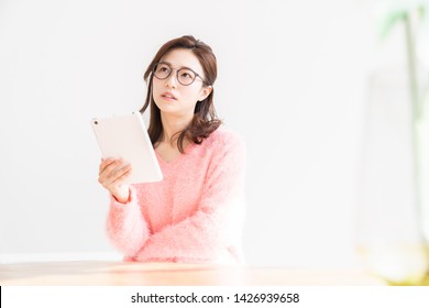 young attractive asian woman to see a tablet computer, think,