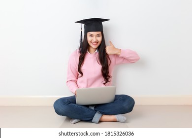 Young attractive Asian woman sitting with laptop on her legs wearing graduated hat, online education class, scholarship study abroad concept. - Shutterstock ID 1815326036