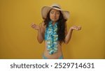 Young attractive asian woman in swimwear and sun hat posing with confused expression over yellow background