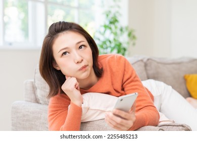 Young attractive Asian woman using a smartphone,think, - Shutterstock ID 2255485213