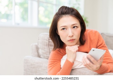 Young attractive Asian woman using a smartphone,think, - Shutterstock ID 2255485231