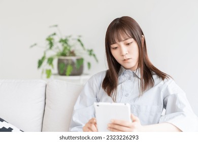 Young attractive Asian woman using a tablet computer,think,