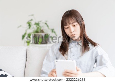 Young attractive Asian woman using a tablet computer,think,