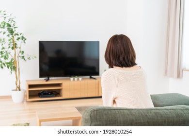 Young Attractive Asian Woman Watching TV In Living Room,back