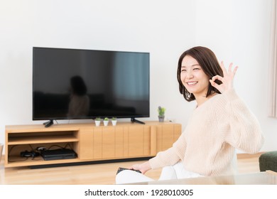 Young Attractive Asian Woman Watching TV In Living Room