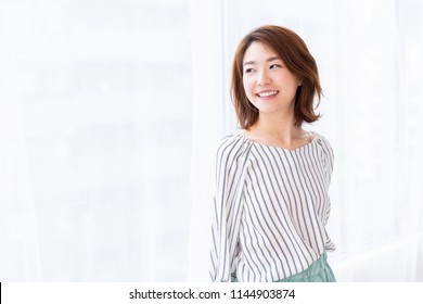 young attractive asian woman who opens a curtain - Powered by Shutterstock