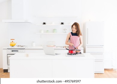 young attractive asian woman who cooks while watching Laptop