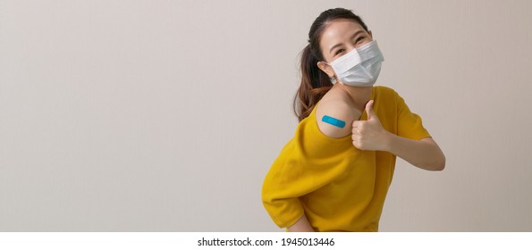 Young attractive beautiful asia female or teenage receive covid-19 anti virus vaccine in campaign vaccination safe life happy smile cheerful with blue, yellow, pink bandage on arm with copy space. - Powered by Shutterstock