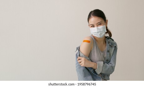 Young attractive beautiful asia female or teenage receive covid-19 anti virus vaccine in campaign vaccination safe life happy smile cheerful with blue, yellow, pink bandage on arm with copy space. - Powered by Shutterstock