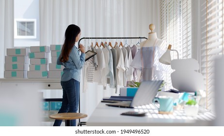 Young attractive beautiful hipster asia female fashion store owner use digital tablet check stock clothes or package box on rail rack at home office small SME business entrepreneur e-commerce concept. - Shutterstock ID 1949496520