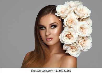 Young attractive beautiful woman with long straight hair. Beautiful girl with white roses near face, natural body skin care