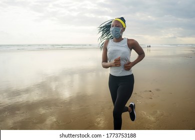 Young Attractive Black Girl Post Quarantine Jogging - New Normal Running Workout Of Athletic And Fit African American Woman At Beautiful Beach Wearing Face Mask