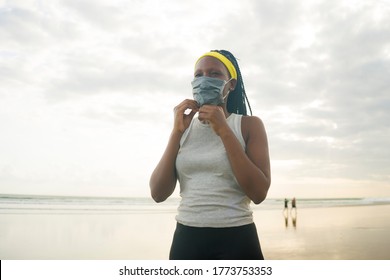 young attractive black girl post quarantine jogging - new normal running workout of athletic and fit African American woman at beautiful beach adjusting face mask - Powered by Shutterstock