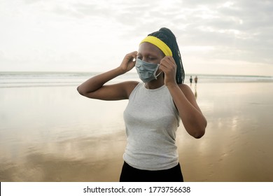 young attractive black girl post quarantine jogging - new normal running workout of athletic and fit African American woman at beautiful beach adjusting her face mask - Powered by Shutterstock