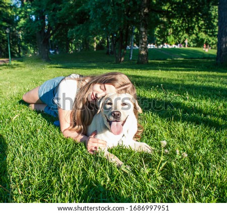 young attractive blond woman playing with her dog in green park at summer, lifestyle people concept