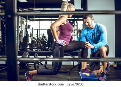 Young attractive blonde female doing lunge exercise in modern fitness center with assistance of her personal trainer. - Powered by Shutterstock