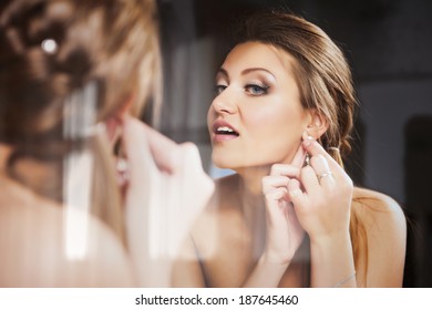 Young Attractive Bride Putting On A Earring