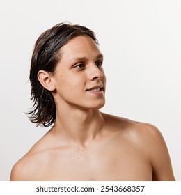 Young attractive brunette man with wet hair posing shirtless against white studio background. Guy looks away. Concept of natural beauty, fashion, cosmetic product, male health. Ad - Powered by Shutterstock