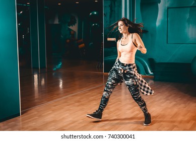 Young Attractive Brunette Woman Doing Zumba Dance Workout Alone In Gym. Toned Image.